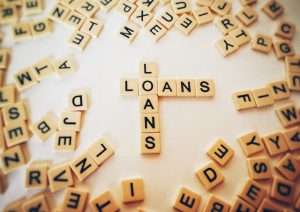 Scrabble tiles spelling "Loans" on board.