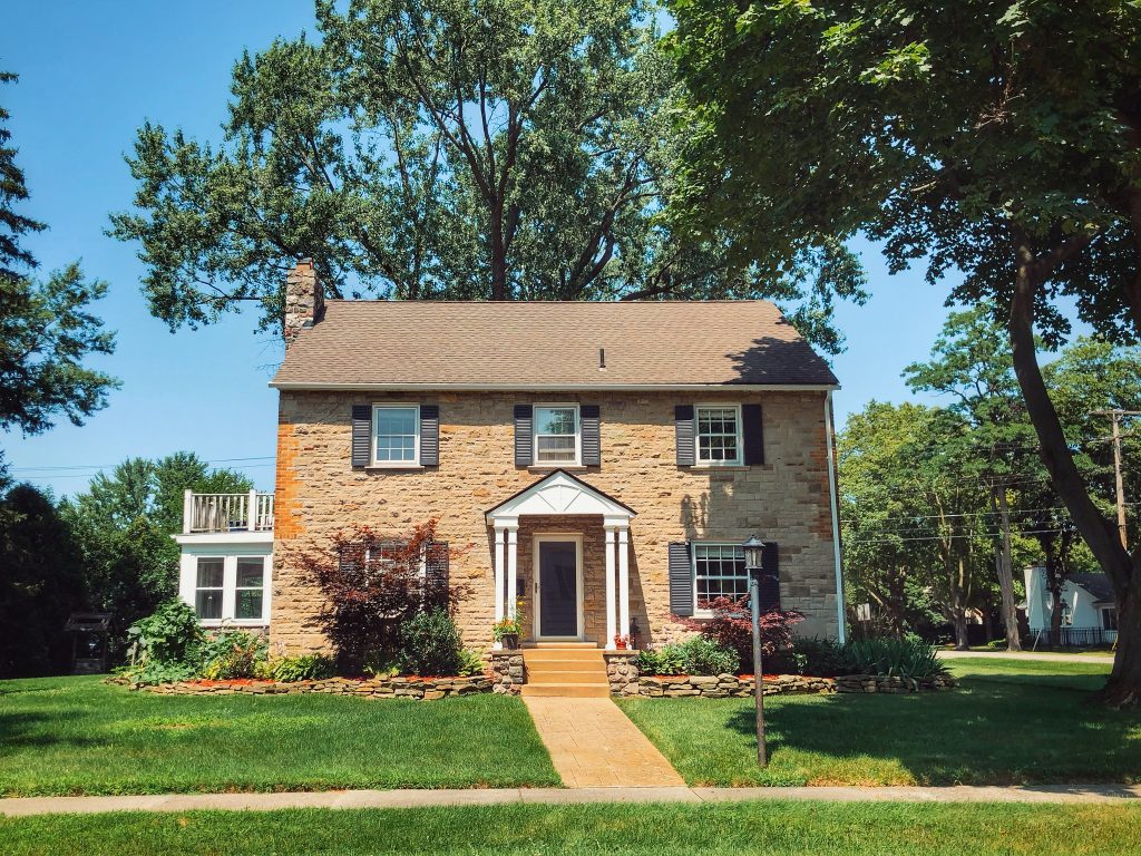 A charming two-story house with a gable roof and lush greenery.